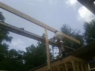 Carpenter setting a ridge beam over a new addition frame — Ice Dam Removal by Roofing Brothers in Garnett
