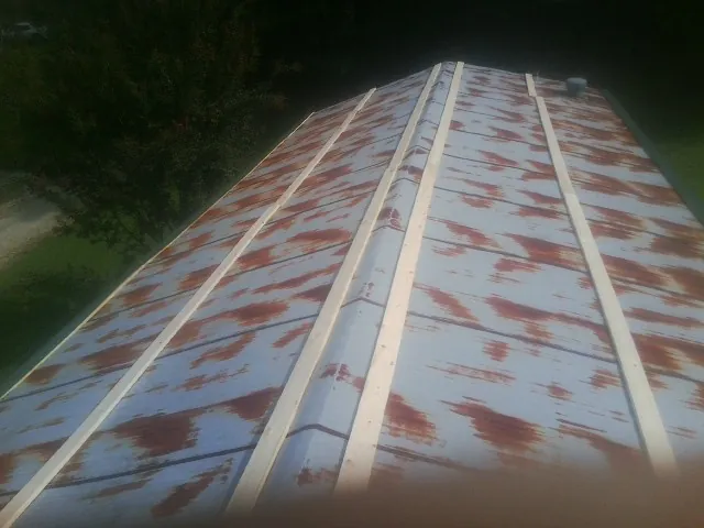 Rusted metal roof panels with new wood purlins before replacement — Storm Damage Roof Repair in Garnett by Roofing Brothers